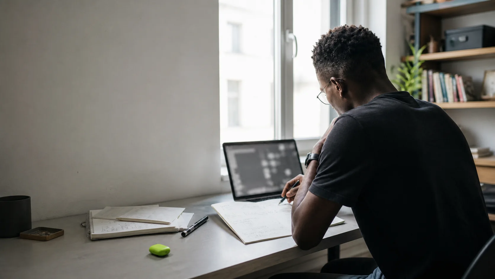 Technical founder reviewing a live product and handwritten market notes in a daylight workspace